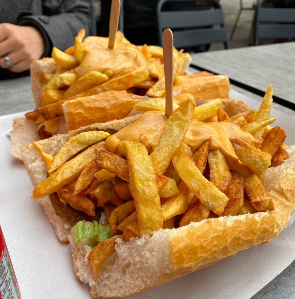 Mitraillette, belgischer Snack mit getoastetem Baguette, Fleisch, Pommes Frites, gebratenen Zwiebeln und köstlicher Sauce, ein sättigender Genuss Spezialitäten in Brüssel