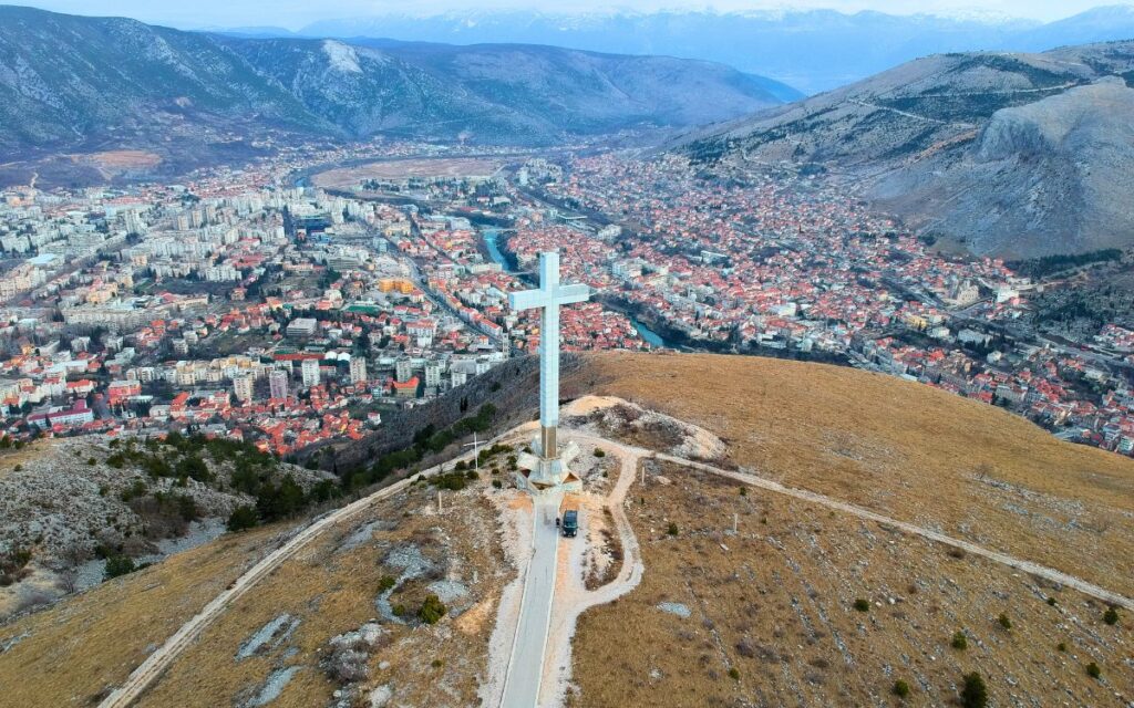 Freistehen am großen Gipfelkreuz auf dem Berg über Mostar mit Panoramablick auf die Stadt und das Umland von Bosnien-Herzegowina.